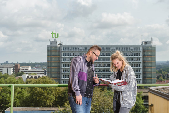 Studierende mit Mathetower im Hintergrund Ein Student und eine Studentin sehen in ein Buch, im Hintergrund ist der Mathetower zu sehen.