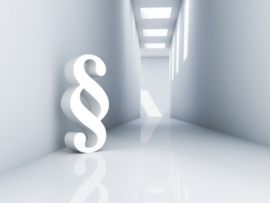 Paragraph im weißen Raum Künstlicher Raum mit überdimensionalem Paragraphenzeichen an der Wand lehnend.