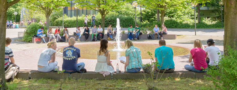 Martin-Schmeißer-Platz Studenten sitzen im Sommer am Brunnen des Martin-Schmeißer-Platzes