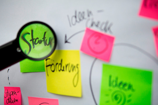 Pinnwand-Klebezettel Beschriftete bunte Klebezettel und eine Lupe, die die Schrift vergrößert.