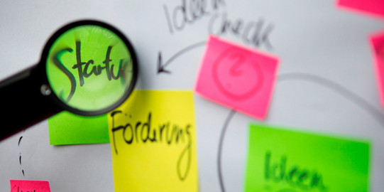 Pinnwand-Klebezettel Beschriftete bunte Klebezettel und eine Lupe, die die Schrift vergrößert.